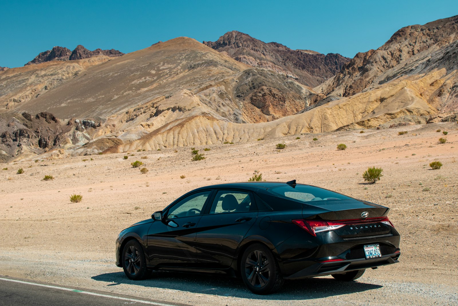 A black car driving down a desert road