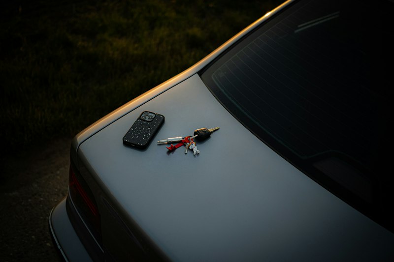 Phone and car keys on a car trunk at sunset